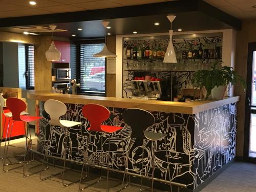 a bar with red and black stools in a restaurant at ibis Toulouse Pont Jumeaux in Toulouse