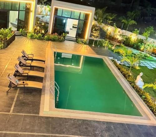 a swimming pool on a building with chairs and a building at Achala Resorts in Maisaram