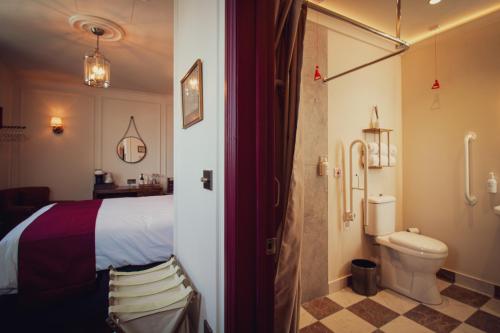a bedroom with a bed and a bathroom with a toilet at The Goat in Boots in London