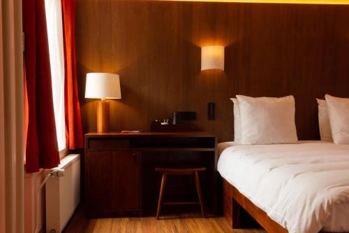 a bedroom with a bed and a desk with a lamp at Hotel The Exchange in Amsterdam