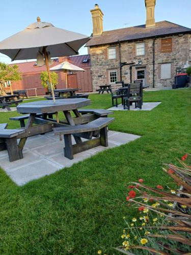 a picnic table with an umbrella in front of a building at Ty'n Llan- tafarn gymunedol- community pub in Llandwrog