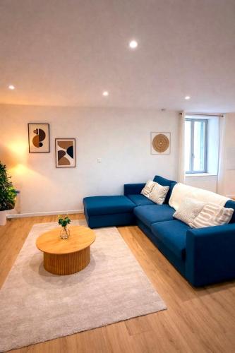 a living room with a blue couch and a coffee table at Le Salon des Voyageurs - Appartement Climatisé avec Terrasse et Parking Gratuit à Proximité in Dole