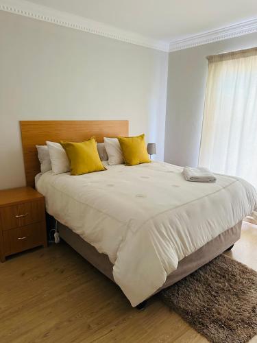 a white bedroom with a large bed with yellow pillows at Kairos Home in Maseru