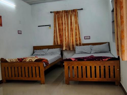 two beds sitting next to each other in a room at S K S HOME STAYs in Vālpārai