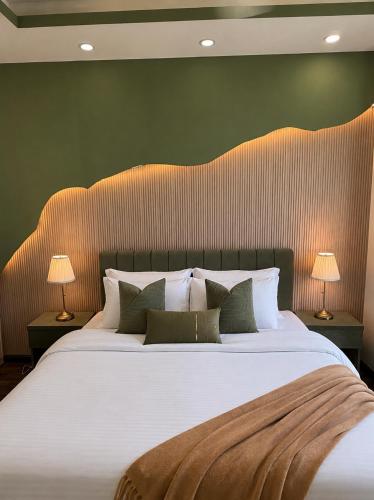 a bedroom with a large white bed with two lamps at ELYSIUM TOWER Luxury Hotel Apartments Facing Centaurus Mall Islamabad in Islamabad
