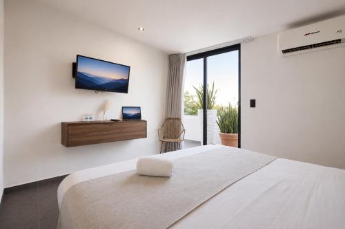 a bedroom with a large bed with a television on the wall at Aruma Suites in Playa del Carmen