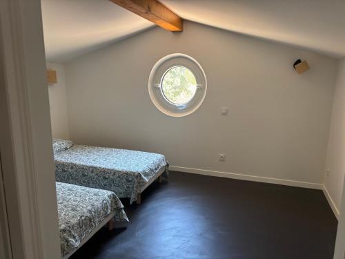 a room with two beds and a round window at Maison récente dans la nature in Roquebrune-sur-Argens