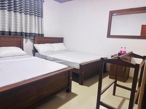 a room with two beds and a mirror at Merlot in Deniyaya