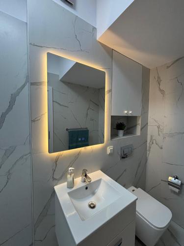 a white bathroom with a sink and a mirror at Oasis-First Estates Pipera in Voluntari