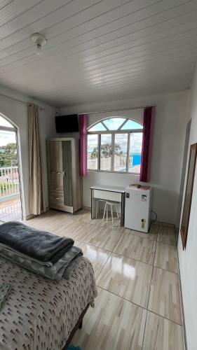 a bedroom with a bed and a desk and window at Pousada Bela Vista in Castro