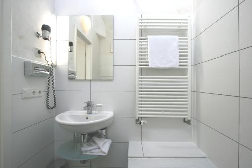 a white bathroom with a sink and a mirror at Chelsea Hotel in Cologne