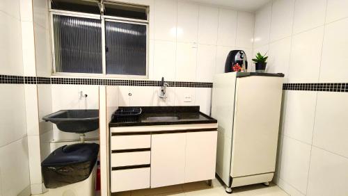 a small kitchen with a sink and a refrigerator at AP 3 quartos -2min da ARENA MRV e Expominas- BH in Belo Horizonte