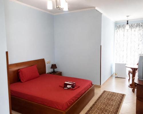 a bedroom with a red bed with a red blanket at Shtepia e Bardhe in Patos