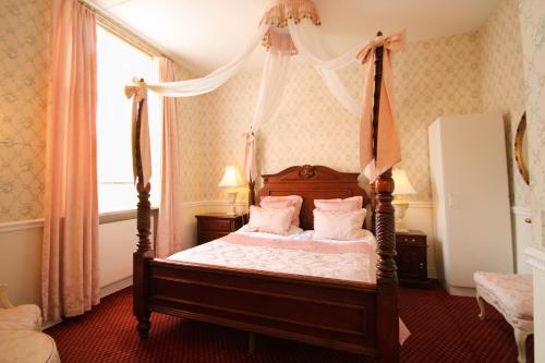 a bedroom with a canopy bed with pink pillows at Sophiendal Manor in Låsby