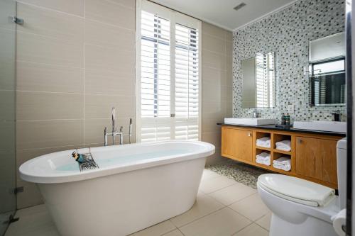 a bathroom with a tub and a toilet and a sink at Isango Gate in Port Elizabeth