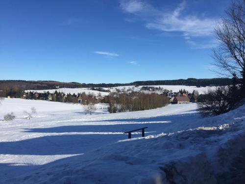 a bench sitting in a snow covered field at Apartmán Kovářská u Klínovce in Kovářská
