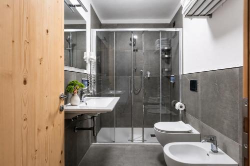 a bathroom with a shower and two sinks and a toilet at Hotel Zanella in Peio Fonti