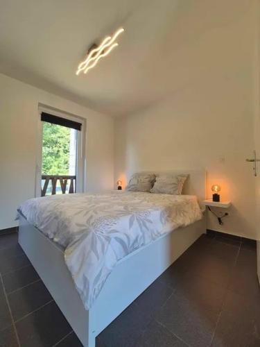a bedroom with a white bed with two lights on it at Studio Le Vedeur in Durbuy