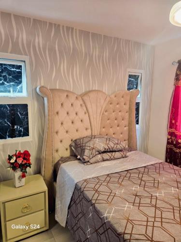 a bedroom with a bed with a headboard and a table at Peace Place in Santiago de los Caballeros