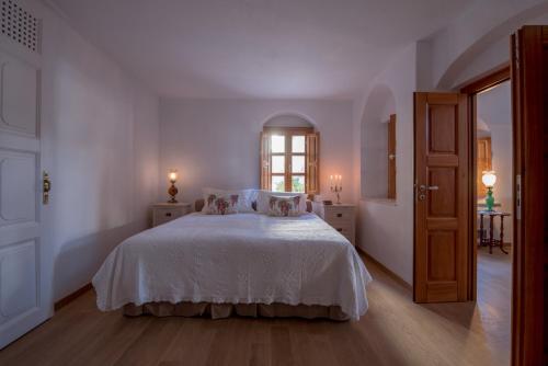 a white bedroom with a bed and a window at Casasantantonio 18th Century Luxury Mansion in Fira