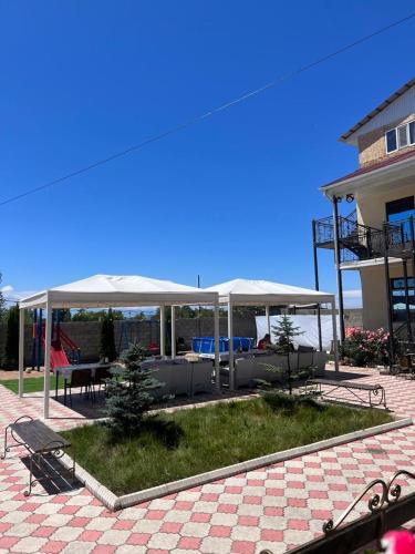 a patio with benches and tables and umbrellas at Aknur Deluxe hotel in Cholpon-Ata