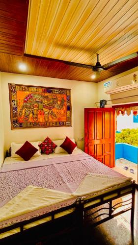 a bedroom with a large bed with a painting on the wall at Mayur Guest House in Pushkar