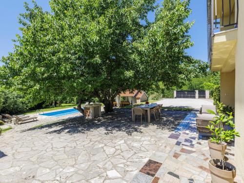 a stone patio with a tree and a pool at Villa Elli by Interhome in Tinjan