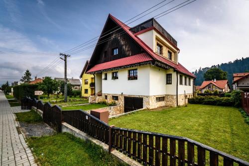 a house with a red roof and a fence at Ubytovanie Filloména in Liptovský Ján