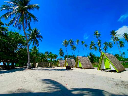 a group of tents on a beach with palm trees at Isla Malaya Tours Campsite in Mantangule Island