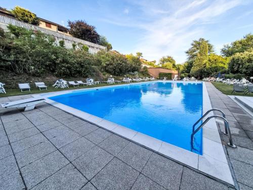 a swimming pool with blue water in a yard at Apartment Lake & Pool by Interhome in Leggiuno