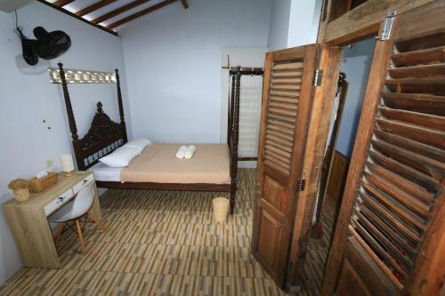 a room with a bed and a desk and a door at Gemyah in Banyuwangi