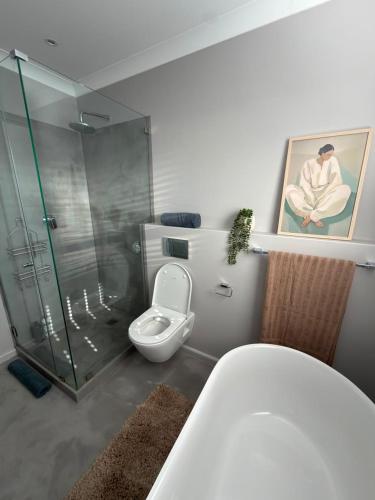 a bathroom with a toilet and a glass shower at Cosy Langdown Getaway in Plettenberg Bay