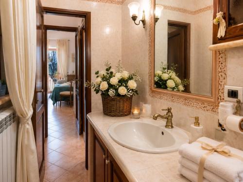 a bathroom with a sink and a mirror and flowers at Maison Vico94 in Vico Equense