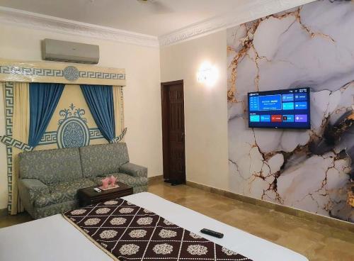 a room with a couch and a tv on a wall at Hotel Imperial Karachi in Karachi