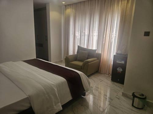 a bedroom with a bed and a chair and a window at Soilsmart Haven in Abuja