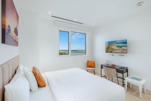 a white bedroom with a bed and a desk at 2 BR Oceanview Condo Coral Shell 3e in Oranjestad