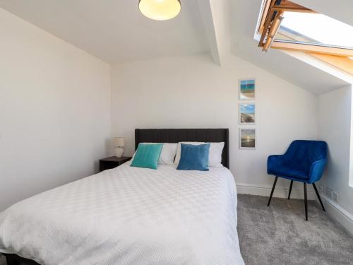 a bedroom with a bed and a blue chair at Ty Haul in Rhosneigr