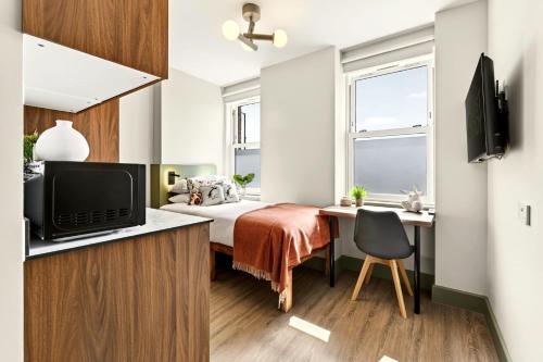 a bedroom with a bed and a desk with a television at GuestReady - The Bridge - Wealdstone in London