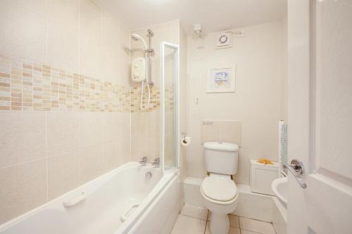 a white bathroom with a toilet and a bath tub at 2 Bed in Bamburgh oc-nb282 in Bamburgh