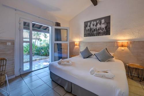a bedroom with a large white bed and a window at Les Rizières in Saintes-Maries-de-la-Mer