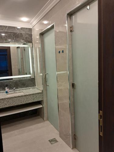 a bathroom with a shower and a sink and a mirror at Muzn al Ghaith Luxury Chalet with Private Pool in Ash Shāghūr