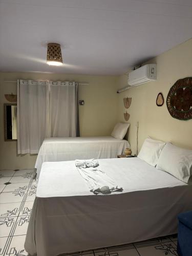 a bedroom with two beds with white sheets at Casa do Professor Hostel in Barreirinhas
