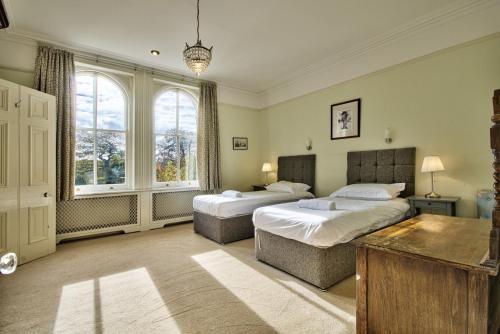 a bedroom with two beds and two windows at Milton House Group Retreats in Bedford