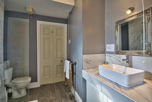 a bathroom with a sink and a toilet and a mirror at Milton House Group Retreats in Bedford