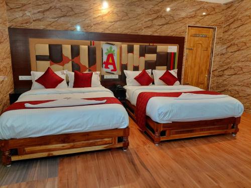 a bedroom with two beds with red pillows at Anbu Grand Inn in Chidambaram