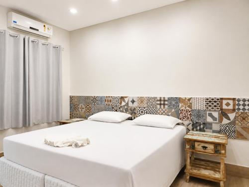 a bedroom with a large white bed and a table at Hotel Pousada Garoupas in São Sebastião