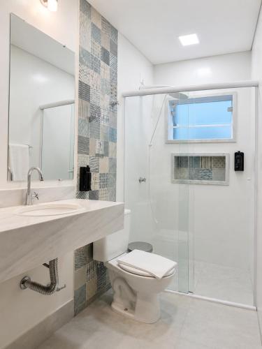 a bathroom with a toilet and a glass shower at Hotel Pousada Garoupas in São Sebastião