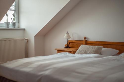 a bedroom with a white bed and a table with a lamp at Penzion Tematin in Piešťany