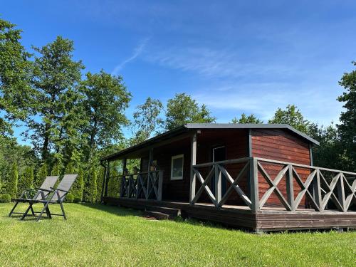 a log cabin with two chairs in the grass at Vienmerjura in Benuži