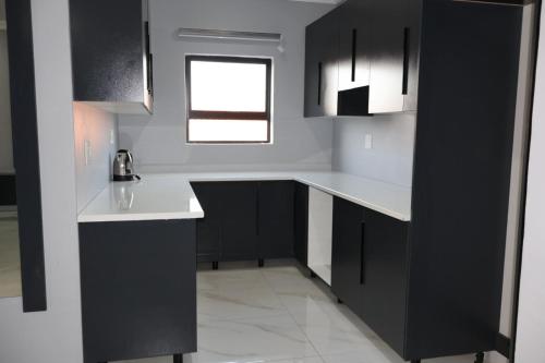 a kitchen with black and white cabinets and a window at The Ulysses Motel in Ga-Mothiba